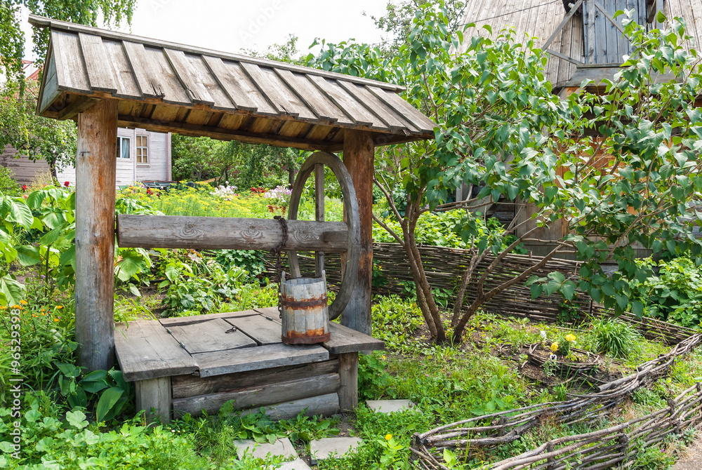 Wooden fence and an old well in the garden of the rural house Wooden fence and an old well in the garden of the rural house