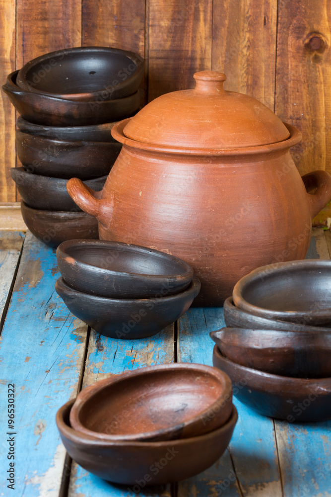 Clay plates and pot on wooden old background Clay plates and pot on wooden old background
