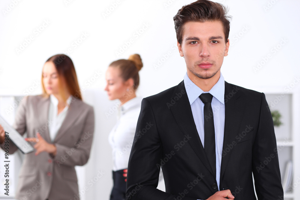 Cheerful business man in office with colleagues in the background, sturt up team Cheerful business man in office with colleagues in the background, sturt up team