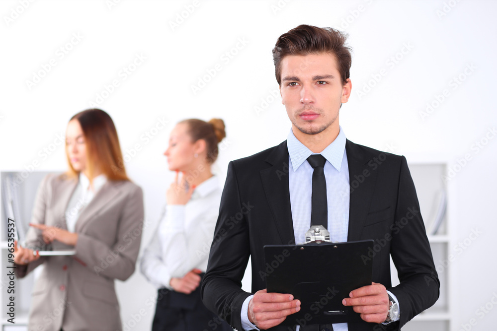 Cheerful business man in office with colleagues in the background, sturt up team Cheerful business man in office with colleagues in the background, sturt up team