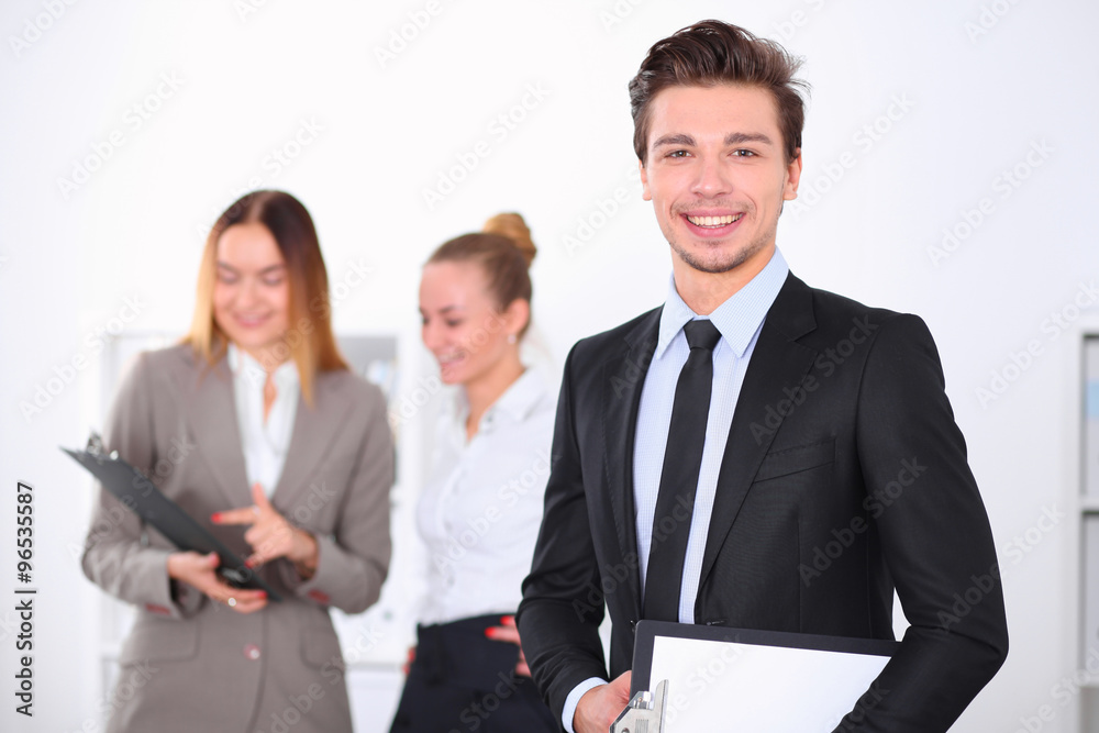 Cheerful business man in office with colleagues in the background, sturt up team Cheerful business man in office with colleagues in the background, sturt up team
