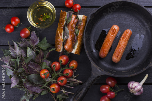 Hot dog with basil, tomato sauce on a brown wooden table