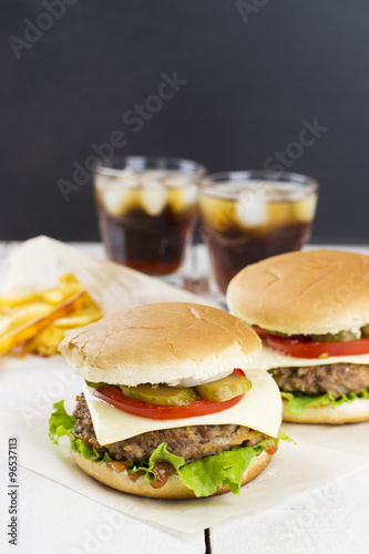 Two burgers, french fries, lemonade on a white wooden background