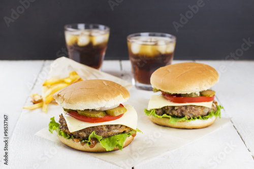Two mini burgers with meat, lettuce, tomatoes, cheese, pickles,