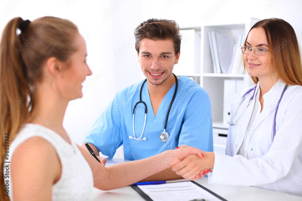 Male doctor and female patient shaking hands. Partnership, trust and medical ethics concept Male doctor and female patient shaking hands. Partnership, trust and medical ethics concept