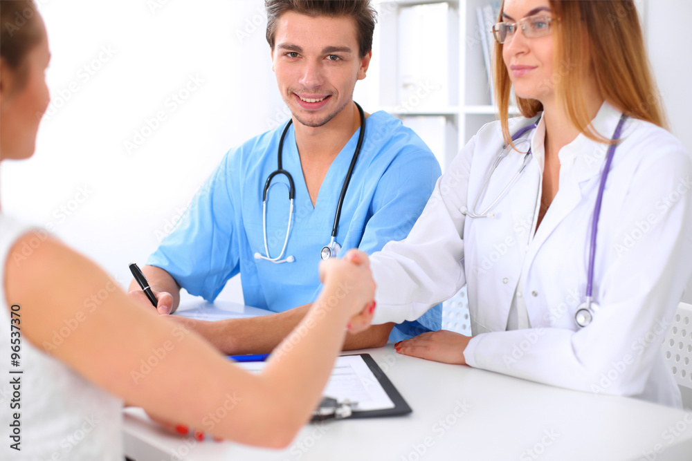 Male doctor and female patient shaking hands. Partnership, trust and medical ethics concept Male doctor and female patient shaking hands. Partnership, trust and medical ethics concept
