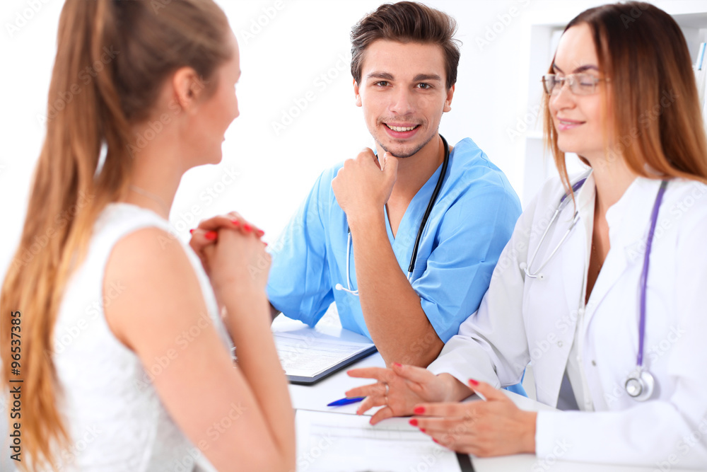 Attractive male doctor surgeon near female doctor and patient discussing, sitting at the desk Attractive male doctor surgeon near female doctor and patient discussing, sitting at the desk