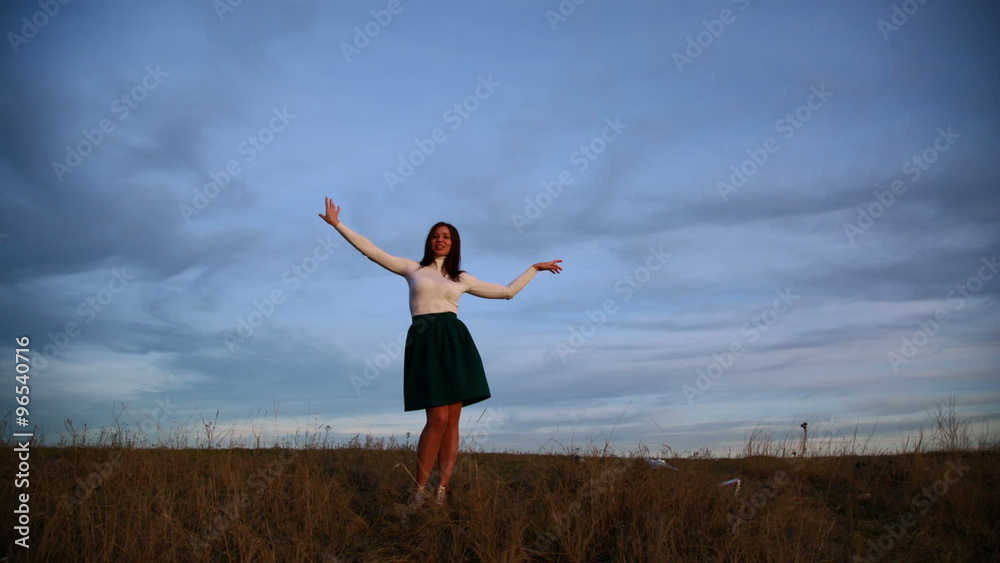 A young woman is dancing against the evening sky A young woman is dancing against the evening sky