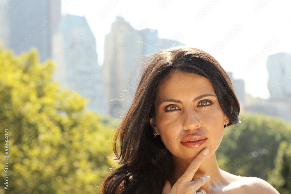 Closeup of an attractive woman with her finger to her chin and Manhattan skyline behind. Closeup of an attractive woman with her finger to her chin and Manhattan skyline behind.