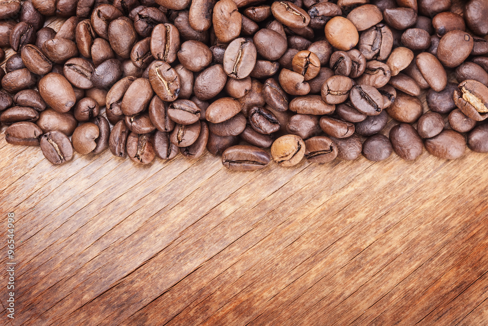 Naklejka premium coffee grains on grunge wooden background closeup