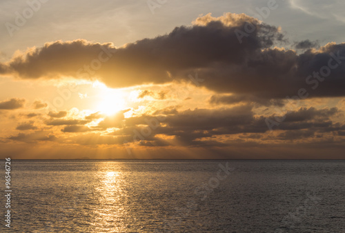 beautiful sunset over the sea with the sun rays through the clou