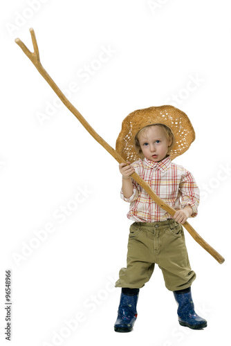 Country boy in straw hat, rubber boots and a long stick in his hand