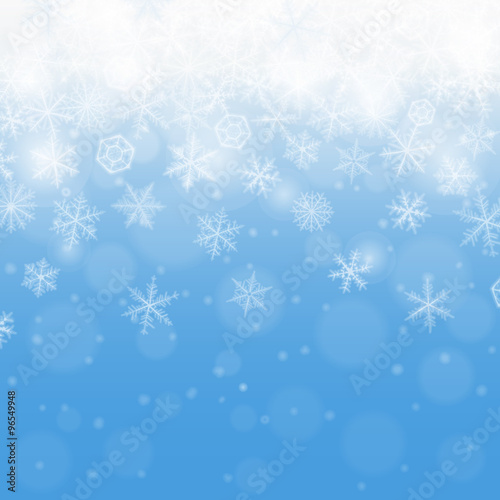 Abstract blue winter background with blurred various snowflakes.