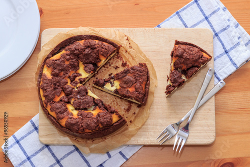 Cheesecake with chocolate shortcrust pastry and chocolate crumble arranged on a wooden board