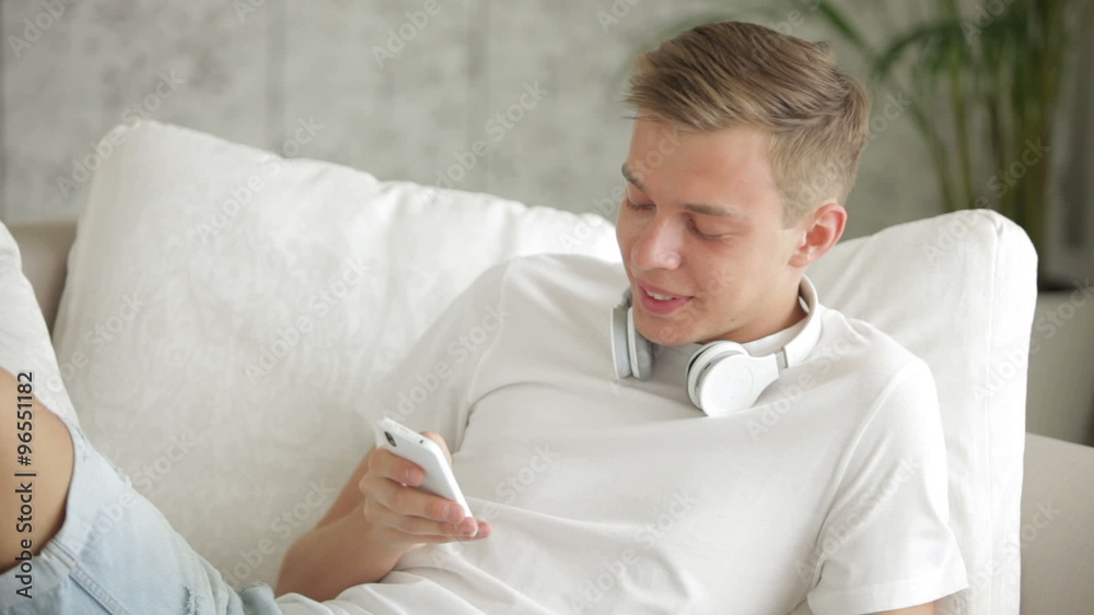 Attractive guy relaxing on sofa using cellphone and eating apple Attractive guy relaxing on sofa using cellphone and eating apple