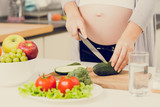 toned photo of pregnant woman making salad on kitchen