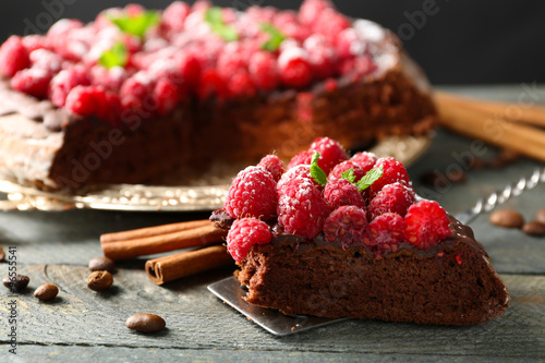 Piece of cake with chocolate Glaze and raspberries on color wooden background