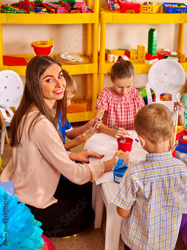 Children with teacher woman painting on paper in  kindergarten