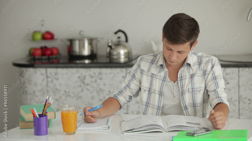 University student studying at table drinking juice and smiling at camera University student studying at table drinking juice and smiling at camera