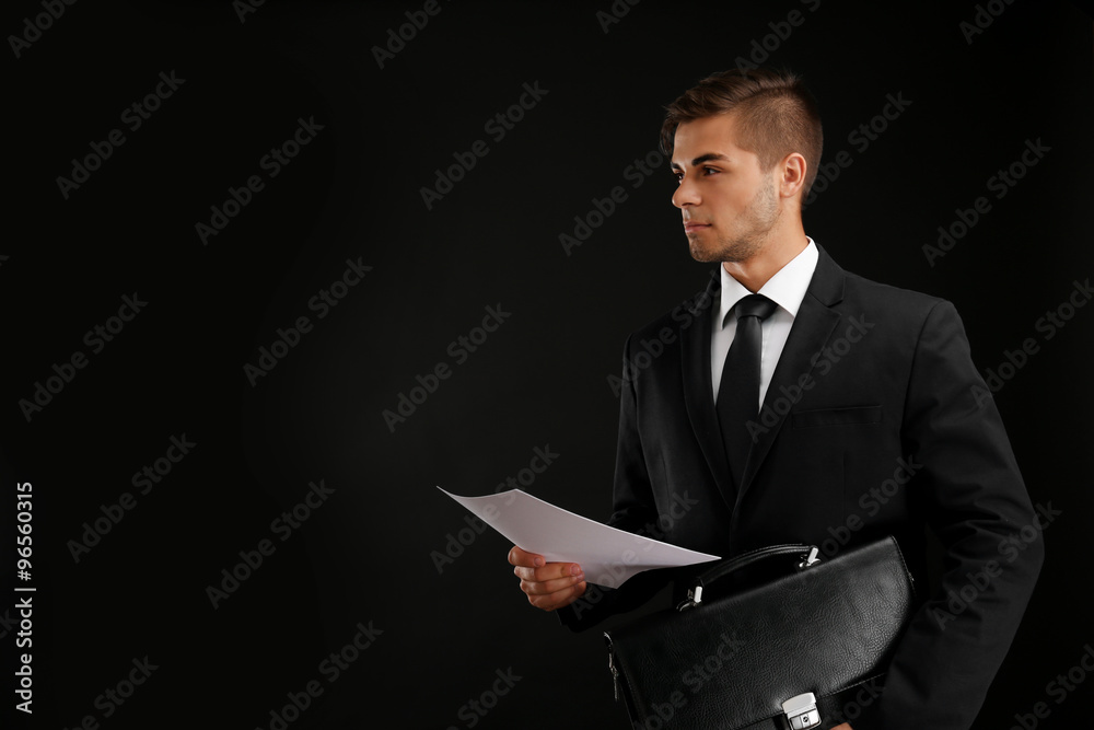 Elegant man in suit with briefcase on dark background Elegant man in suit with briefcase on dark background