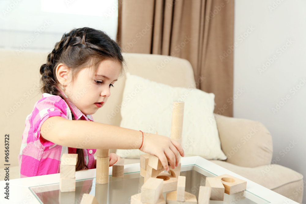 Little girl playing with cubes on home interior background Little girl playing with cubes on home interior background