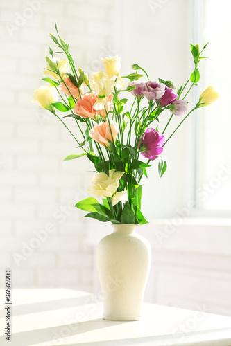 Beautiful spring flowers in vase on window background