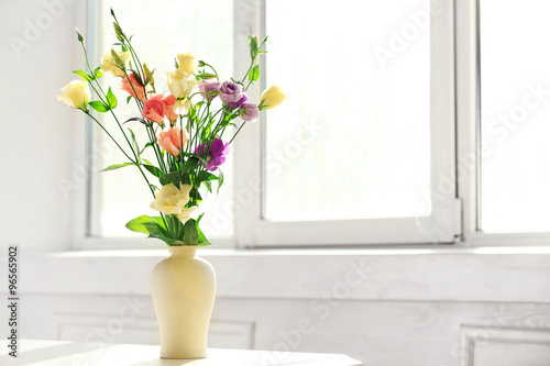 Beautiful spring flowers in vase on window background