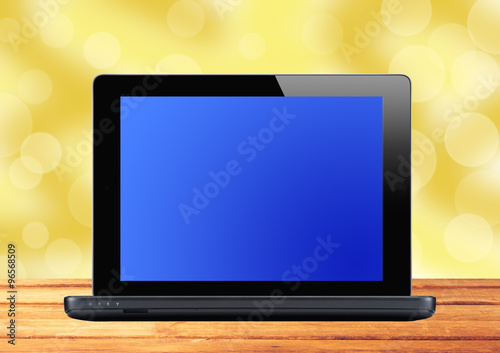 Black laptop on wooden table over blurred background