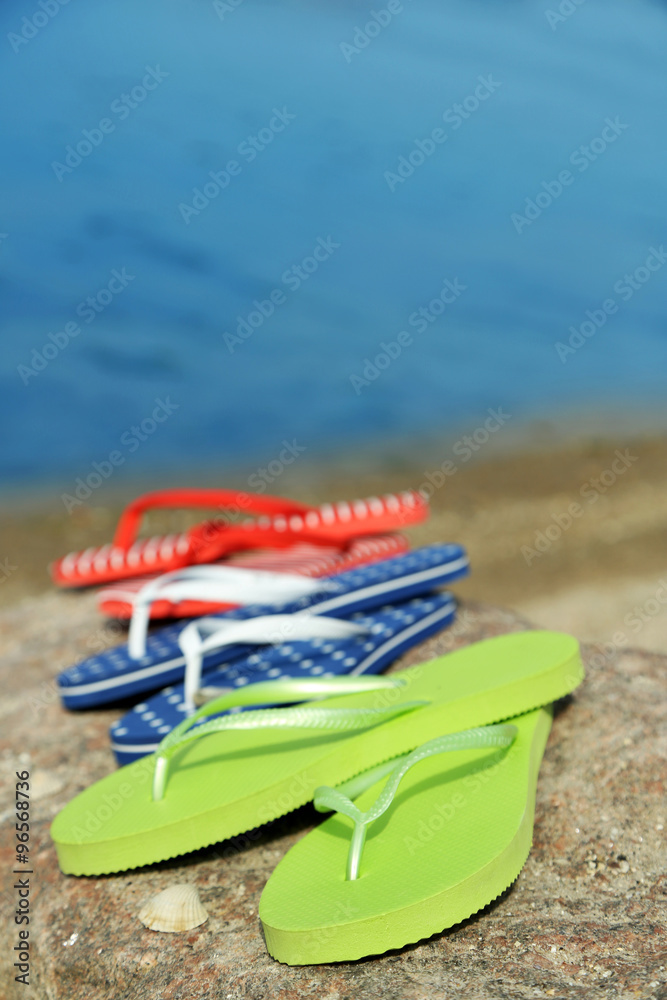 Bright flip-flops on stone, nature background Bright flip-flops on stone, nature background