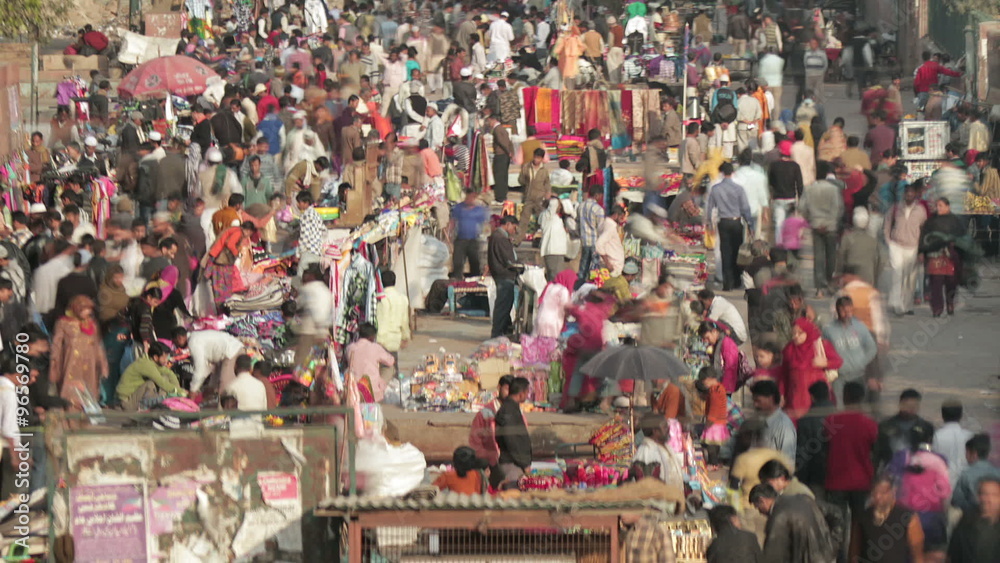 Time-lapse of crowds in street market in Delhi, India. Camera pans left to right