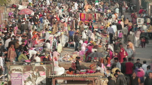 Time-lapse of crowds in street market in Delhi, India. Camera pans left to right
