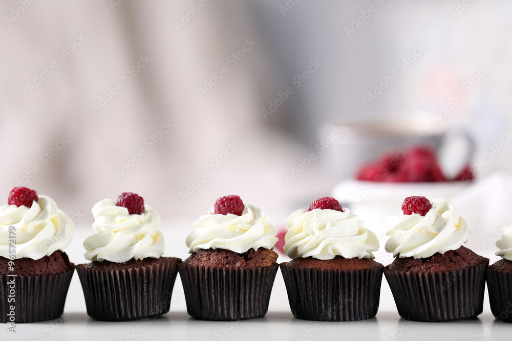 Beautiful chocolate cupcakes with cream and raspberry on table Beautiful chocolate cupcakes with cream and raspberry on table