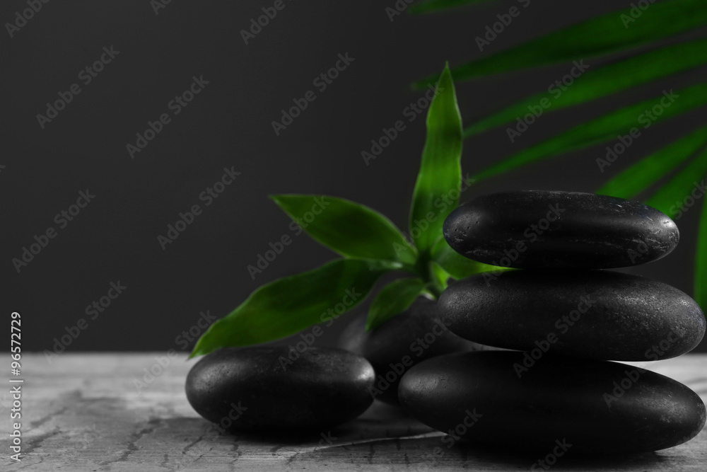 Black spa stones and green flowers, on dark grey background Black spa stones and green flowers, on dark grey background