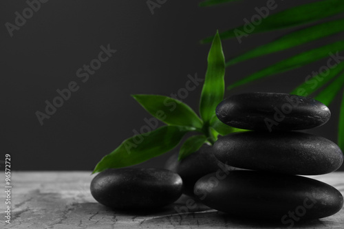 Black spa stones and green flowers  on dark grey background