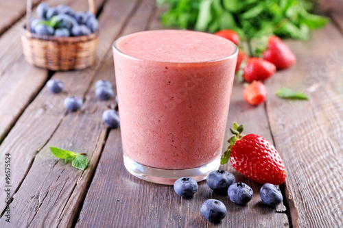 A glass of fresh cold smoothie with berries, on wooden background
