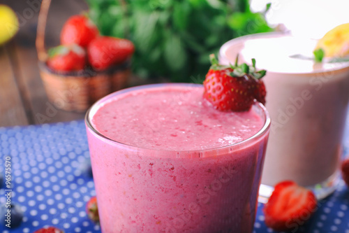 Glasses of fresh cold smoothie with fruit and berries, on blue tablecloth background, close-up