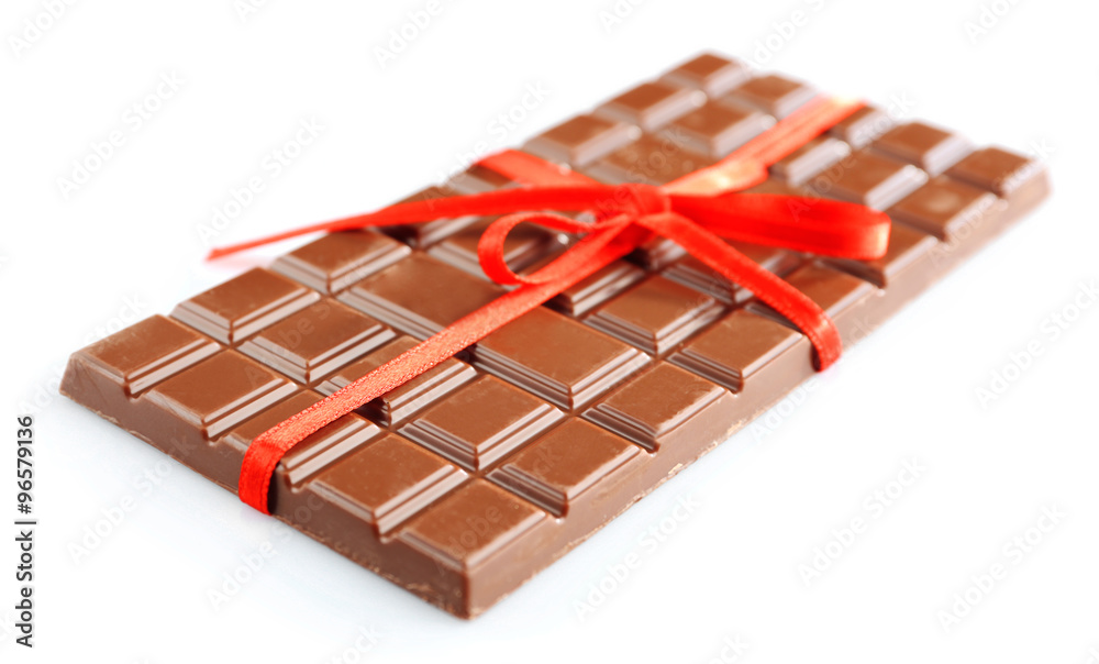 Milk chocolate bar with red bow on color wooden background Milk chocolate bar with red bow on color wooden background