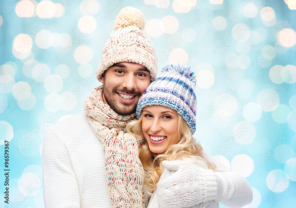 happy couple in winter clothes hugging over lights