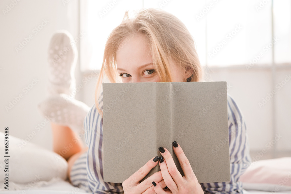 Flirty shy young woman covered her face by the book Flirty shy young woman covered her face by the book