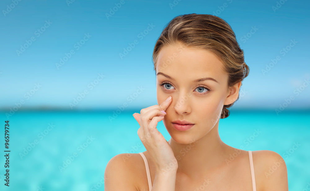 young woman applying cream to her face young woman applying cream to her face