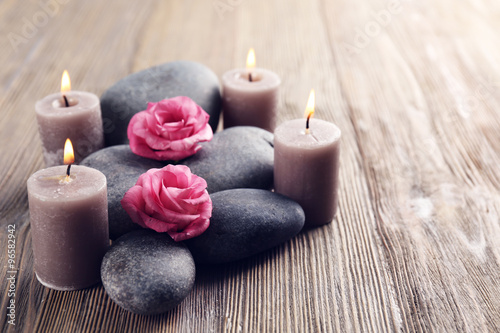 Alight wax grey candles with roses and pebbles on wooden background - relax concept