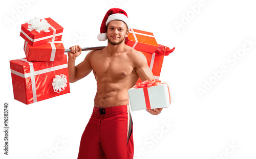 Christmas fever. Young fit guy with hot body holding out one of his presents isolated on white background with a copyplace on the side photo