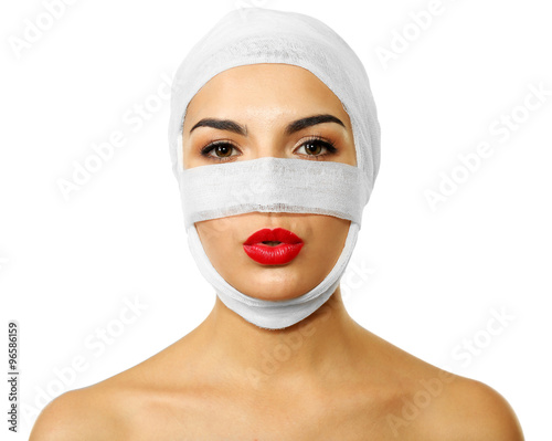 Young beautiful woman with a gauze bandage on her head and nose, isolated on white photo