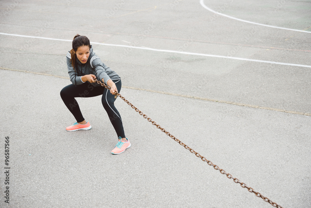 Fitness woman pulling chain for strength workout