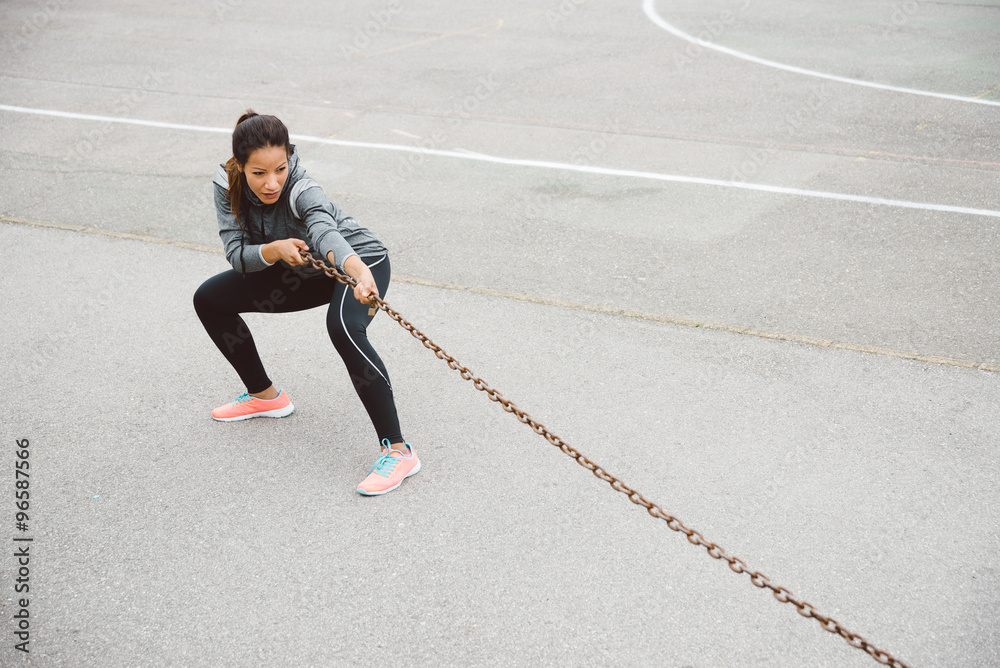 Fototapeta premium Fitness woman pulling chain for strength workout