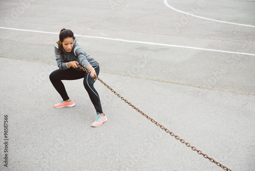 Fitness woman pulling chain for strength workout