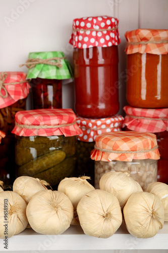 Jars with pickled vegetables and beans on wooden shelf © Africa Studio