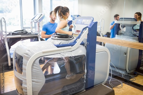 Woman using an anti gravity treadmill beside trainer