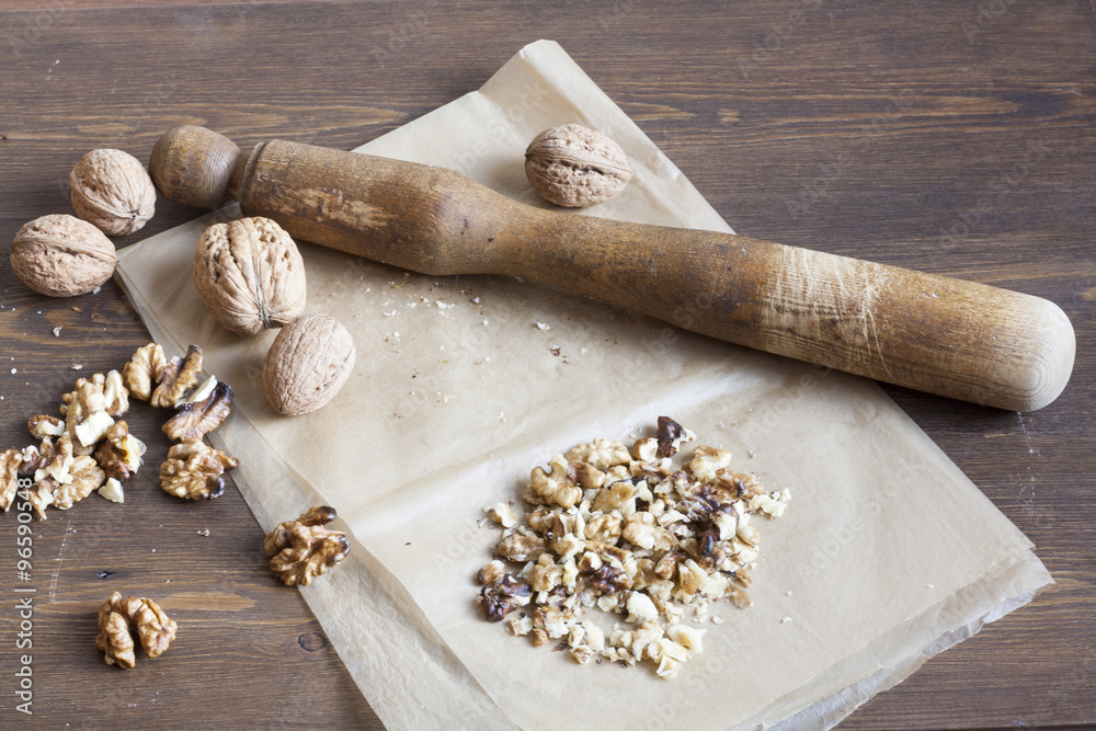 Walnuts in paper and wood battledore on a wooden background Walnuts in paper and wood battledore on a wooden background