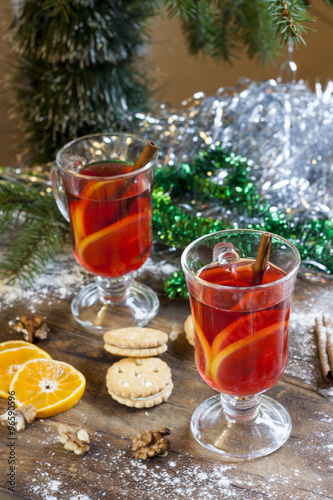 Tea with lemon, tangerines, cookies and nuts in Christmas decor with Christmas tree, nuts and apples on colorful background bokeh